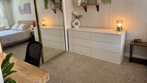 A bedroom with a bed, a dresser, a mirror, a desk, and shelves with plants. - Elmira 1-bedroom guesthouse in beautiful Aurora (Aurora)