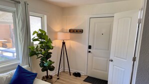 A room with a sofa, a potted plant, a floor lamp, a door, and a window. - Elmira 1-bedroom guesthouse in beautiful Aurora (Aurora)
