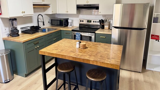 A modern kitchen with white cabinets, a stainless steel refrigerator, a microwave, a coffee maker, and a blender. - Elmira 1-bedroom guesthouse in beautiful Aurora (Aurora)