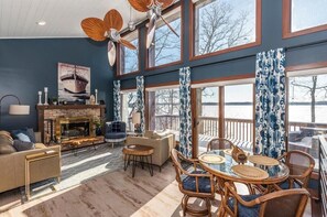 Ein geräumiges Wohnzimmer mit Kamin, großen Fenstern und Blick auf das Wasser.
