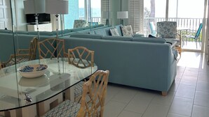 Ein modernes Wohnzimmer mit einem Glastisch, Korbstühlen, einem blauen Sofa und einem Deckenventilator.