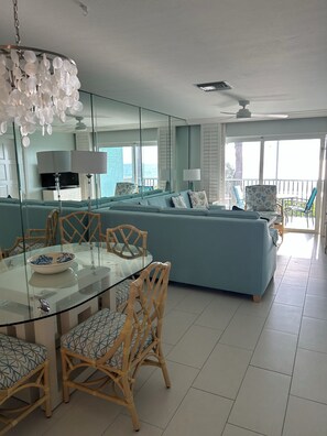 Ein modernes Wohnzimmer mit einem Glastisch, Korbstühlen, einem blauen Sofa und einem Deckenventilator.