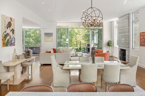 Una sala de estar moderna con comedor, ventanas grandes y chimenea.