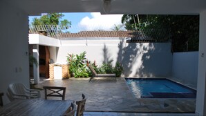 Une terrasse avec une piscine, une table à manger et des chaises.
