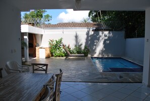 Eine Terrasse mit Pool, Esstisch und Stühlen.