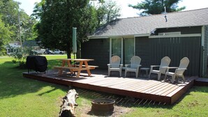 A deck with chairs, a table, and a grill. - Charming 2-bedroom Lake Cottage (Durhamville)