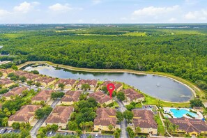 An aerial view of a residential area with houses, a swimming pool, and a lake. - Sunshine Stay Near Disney  2BR  Walk to Pool (Kissimmee)
