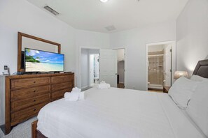 A hotel room with a bed, a wooden dresser, a television, and a bathroom visible through an open door. - Sunshine Stay Near Disney  2BR  Walk to Pool (Kissimmee)