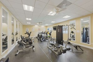 Ein Fitnessstudio mit Cardiogeräten, Krafttrainingsausrüstung und Spiegeln an den Wänden.