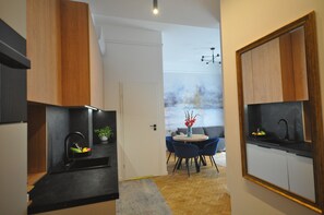 Una cocina moderna con encimera negra, armarios de madera y un comedor con una mesa redonda y sillas azules.