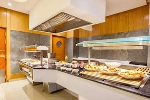 Disposição de buffet com diversos alimentos, sistema de ventilação e design de cozinha moderno.