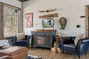 Una habitación con un ventanal grande, un armario de madera, dos sofás de cuero y un espejo.