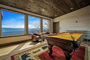A pool table in a room with large windows, a red rug, and a view of mountains. - 7-Bedroom Luxury Cabin with Indoor Pool, Rooftop & Pickleball Court (Sevierville)