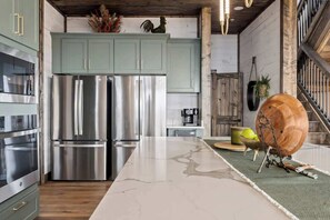 A kitchen with stainless steel appliances, light green cabinets, and a marble countertop. - 7-Bedroom Luxury Cabin with Indoor Pool, Rooftop & Pickleball Court (Sevierville)