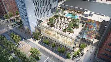 A modern building with a rooftop pool, outdoor seating, and a mural.