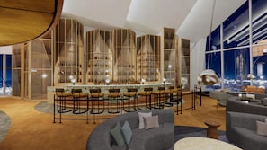 A modern bar area with a bar counter and seating, surrounded by tall shelving units with bottles.