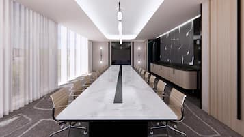 A conference room with a long table, chairs, a projector screen, and a large window.