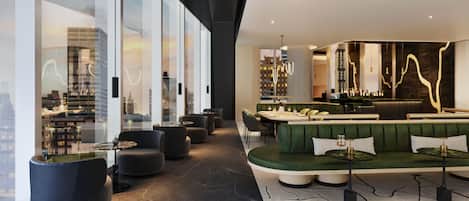 A modern interior with a green sofa, black armchairs, and a bar area.