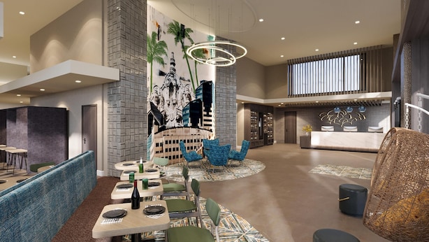 A modern hotel lobby with a reception desk, seating areas, and a decorative wall.