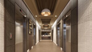 A hallway with elevators and a kitchen area visible in the distance.
