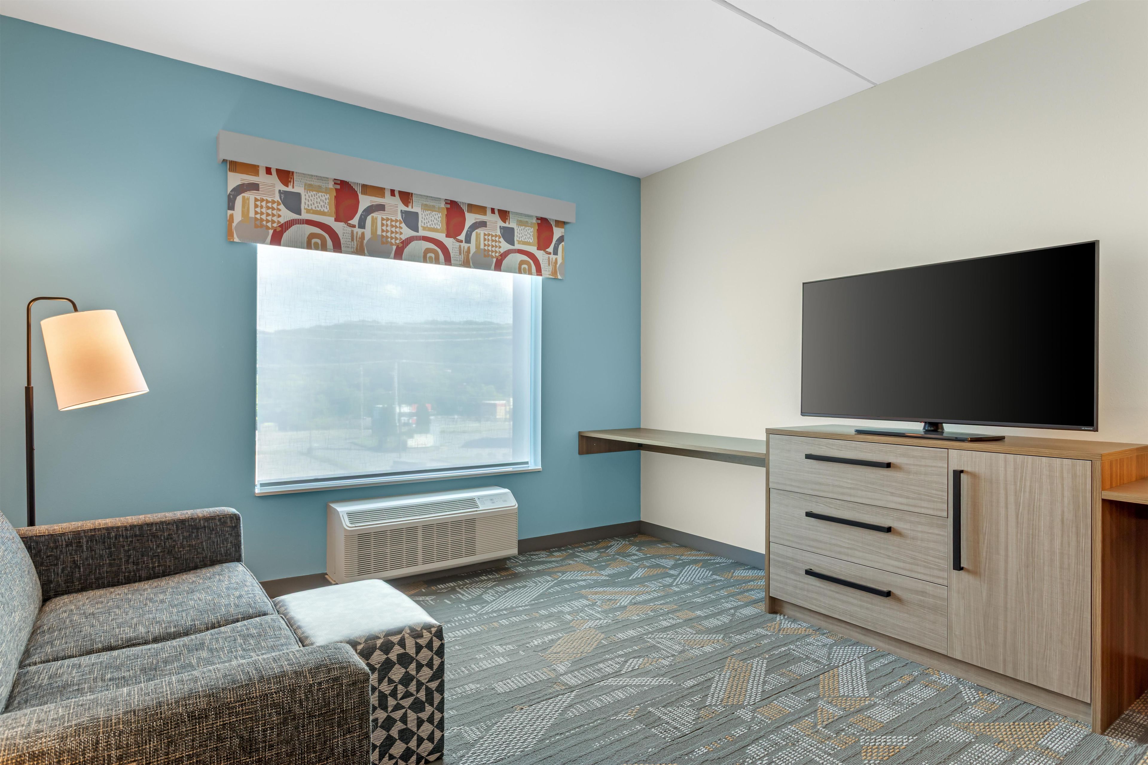 A room with a sofa, a flat-screen TV, a radiator, and a patterned rug.