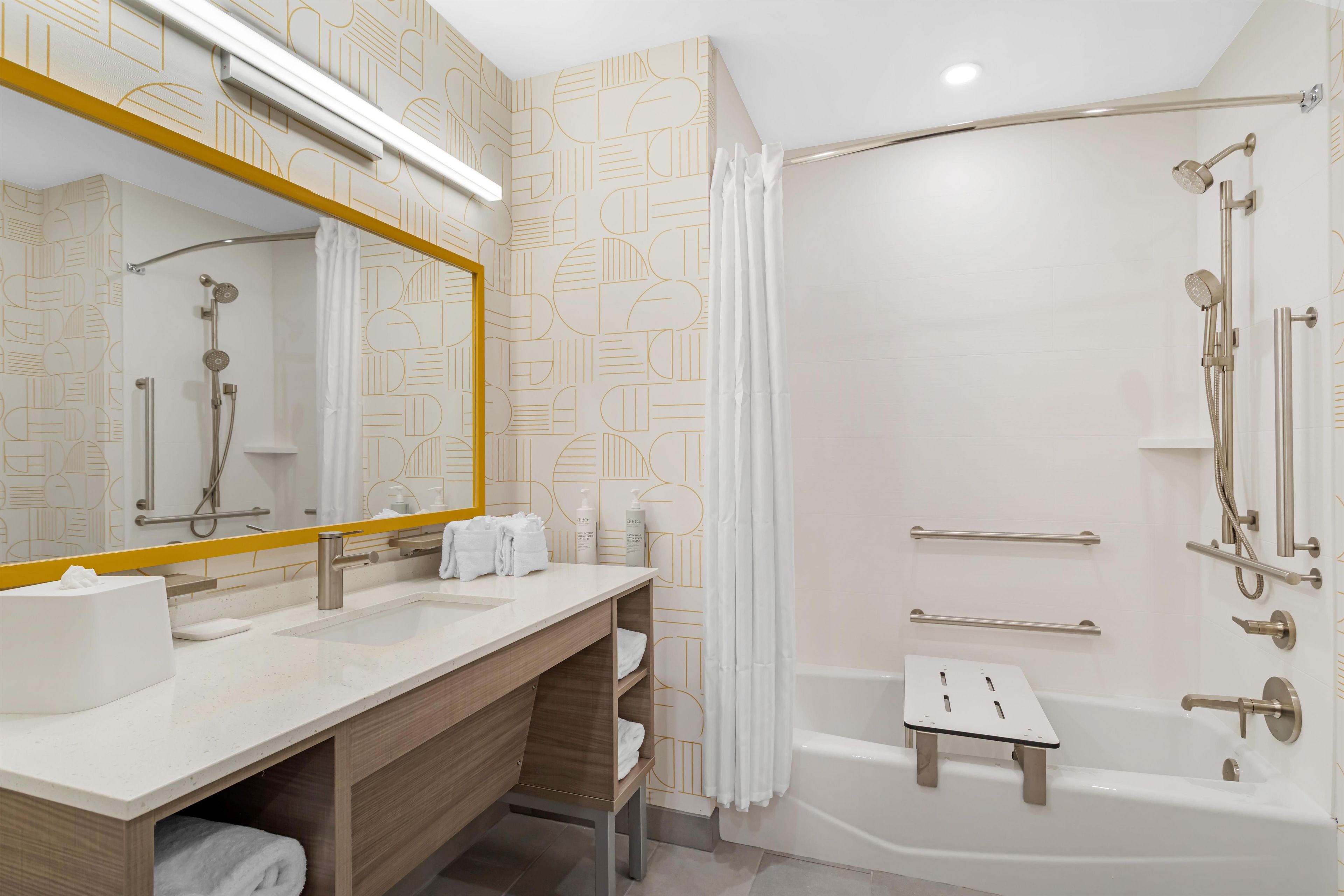 A modern bathroom with a large mirror, a bathtub, and a shower area.