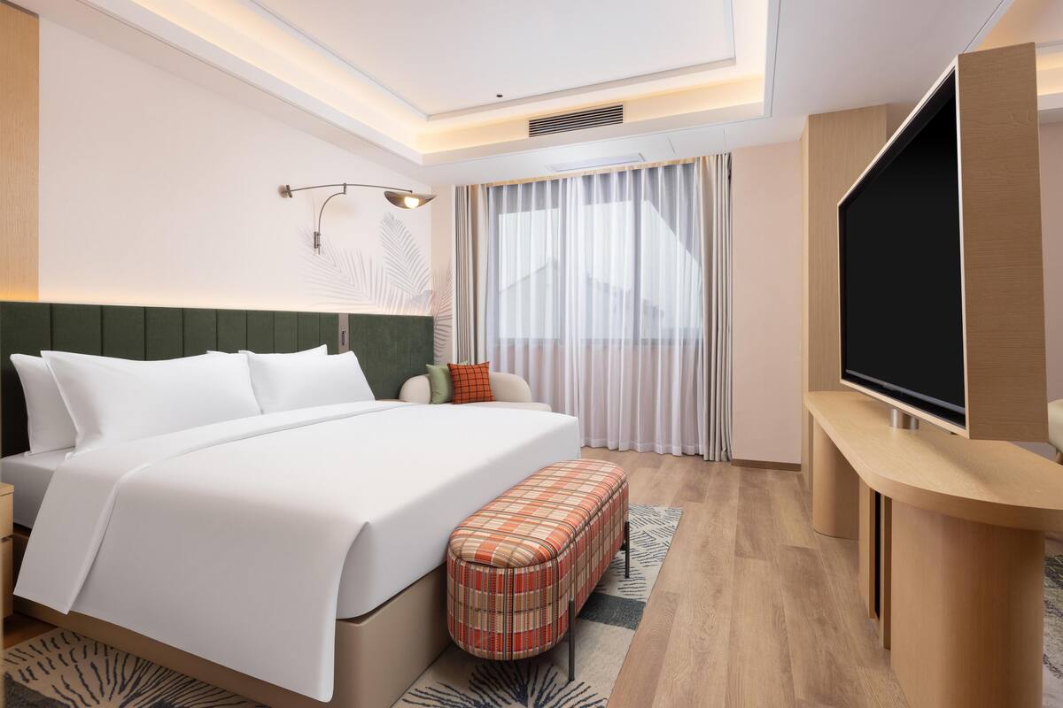 Ein modernes Hotelzimmer mit einem großen Bett, einem Flachbildfernseher und einem Schreibtisch.