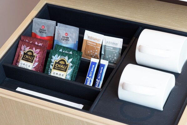 Un cajón con varios paquetes de té y dos objetos blancos.