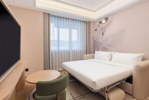 Una habitación de hotel con una cama, un escritorio, una silla, un televisor y una ventana con cortinas.