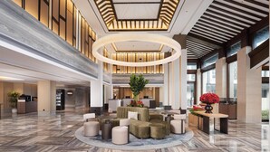 A spacious lobby with a central seating area, a reception desk, and a large plant. - Hilton Garden Inn Tongxiang Wuzhen (Jiaxing)
