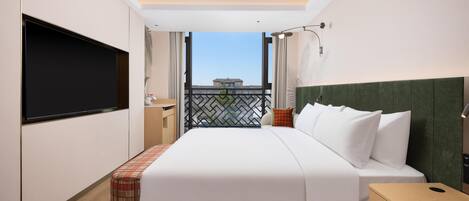 A hotel room with a bed, a TV, a nightstand, a bedside table, a window with a view, and a balcony.