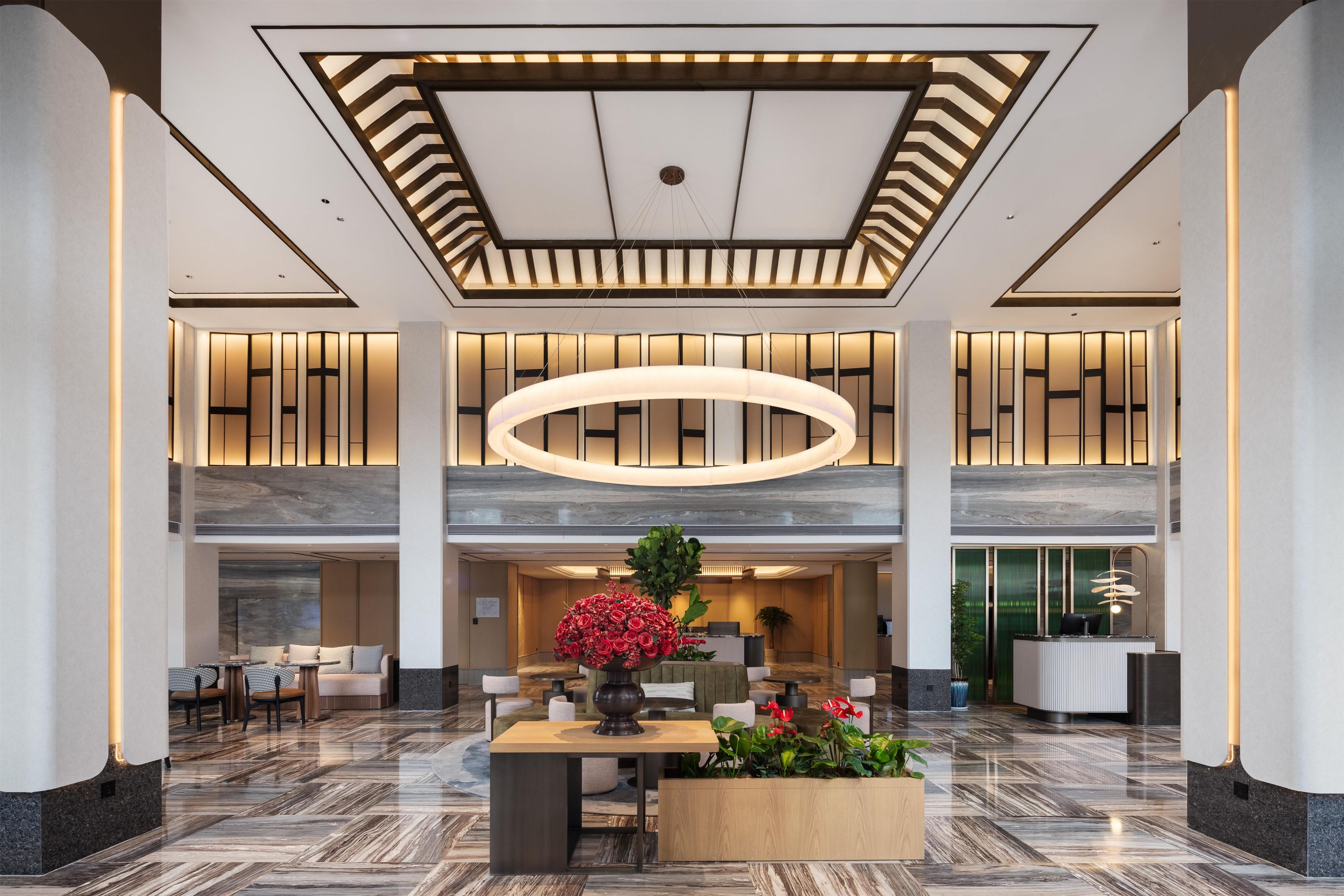 Un vestíbulo amplio con una recepción central, zonas de estar y un arreglo floral decorativo.