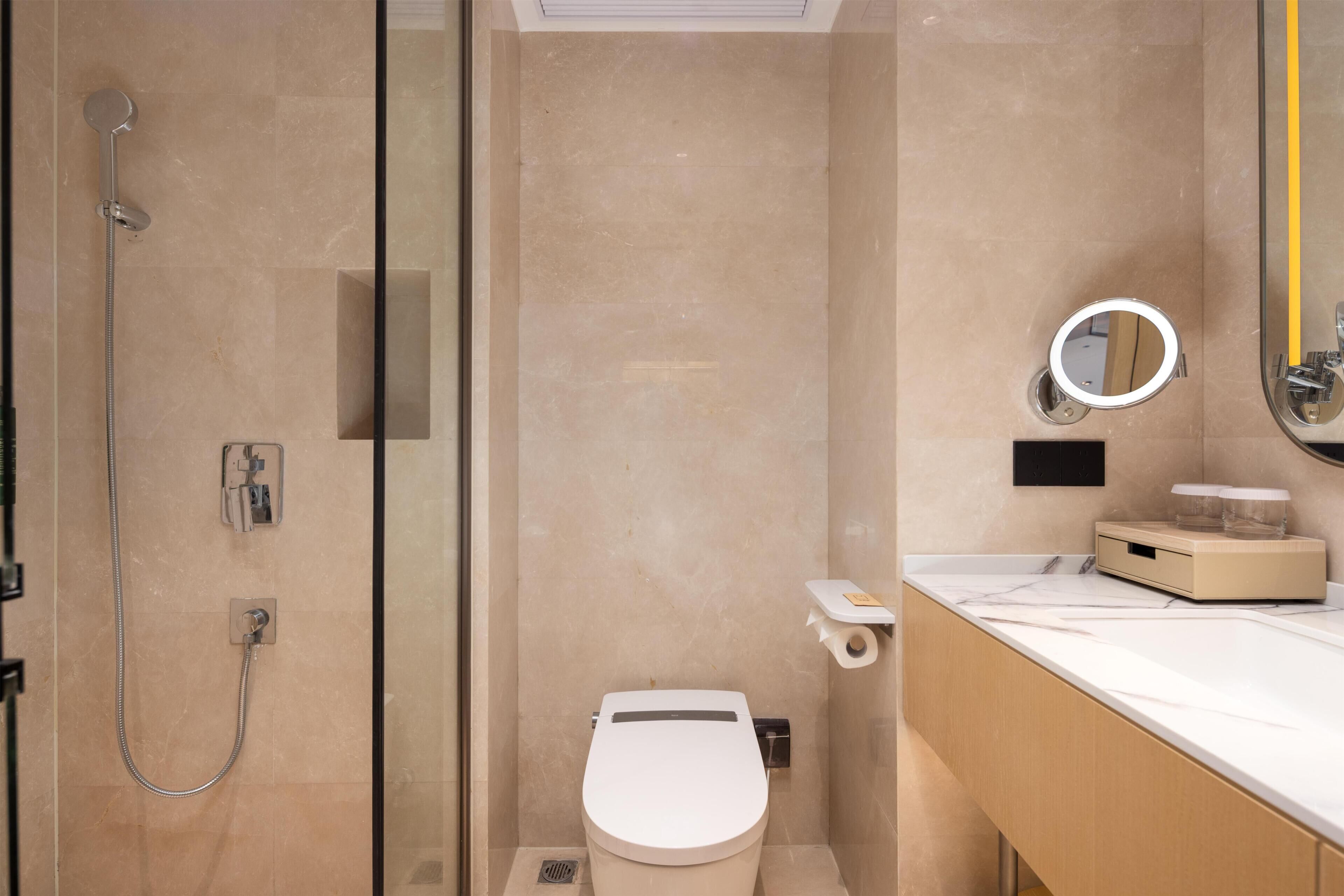 Une salle de bain moderne avec une douche à parois de verre, des toilettes et un meuble-lavabo avec un miroir.