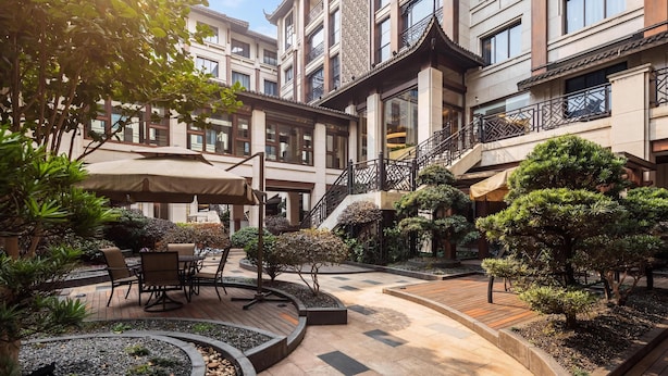 A courtyard with outdoor seating, a staircase, and a building with traditional architectural elements. - Hilton Garden Inn Tongxiang Wuzhen (Jiaxing)