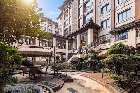 A courtyard with outdoor seating, a staircase, and a building with traditional architectural elements.
