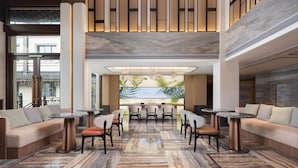 A modern lobby with a seating area, a large wall-mounted screen, and a high ceiling with recessed lighting. - Hilton Garden Inn Tongxiang Wuzhen (Jiaxing)