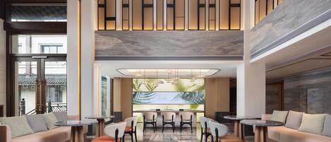 A modern lobby with a seating area, a large wall-mounted screen, and a high ceiling with recessed lighting.