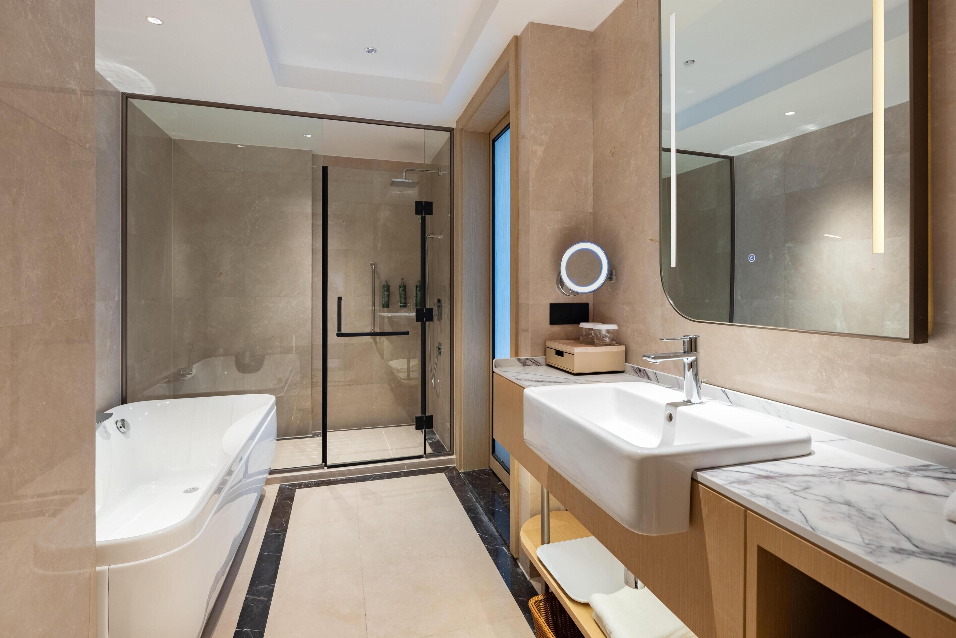 Une salle de bain moderne avec une douche à parois de verre, une grande baignoire et un meuble-lavabo avec un miroir.