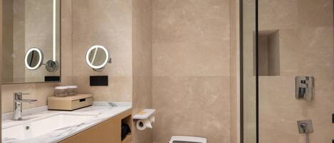 A modern bathroom with a marble sink, two round mirrors, a toilet, and a glass-enclosed shower.