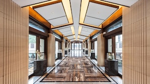 A modern hallway with a polished marble floor, large windows, and a symmetrical ceiling design. - Hilton Garden Inn Tongxiang Wuzhen (Jiaxing)