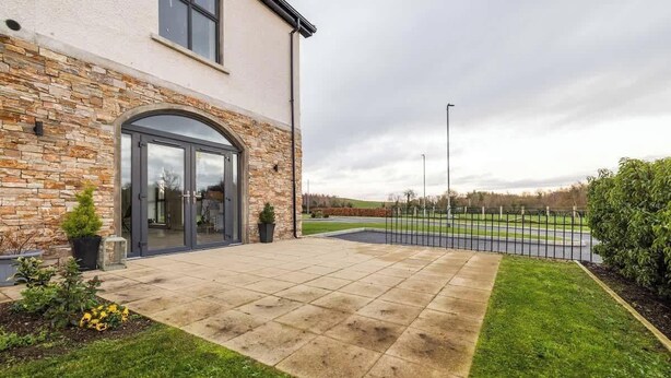A modern building with a stone facade, a large arched entrance, and a paved patio area. - Homestead Hillsborough, Triple Deluxe Suite (Hillsborough)