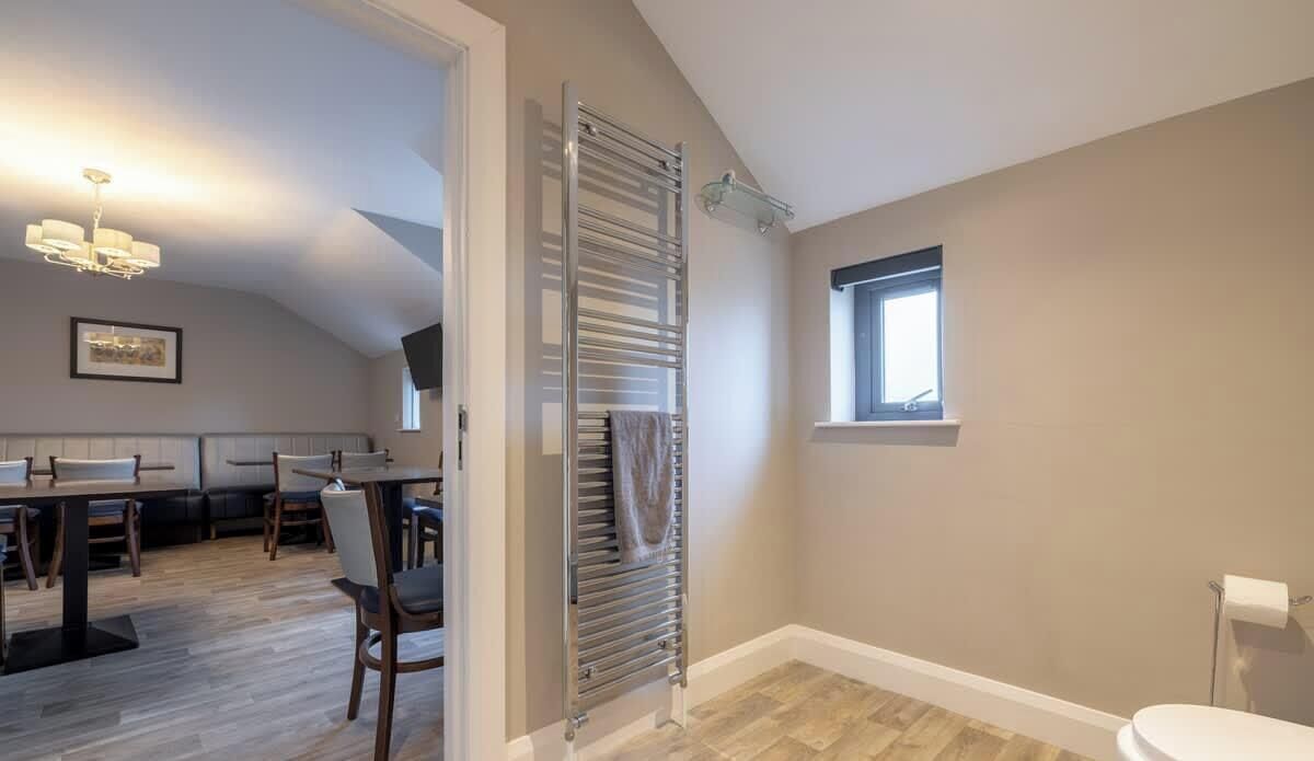 A room with a dining area, a radiator, a window, and a toilet.