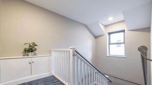 A staircase with a white railing, a potted plant, and a window on the upper landing. - Homestead Hillsborough, Triple Deluxe Suite (Hillsborough)