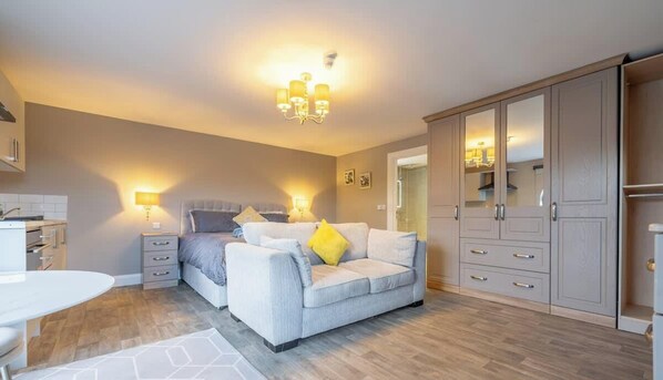 A bedroom with a bed, bedside tables, a sofa, and a wardrobe.