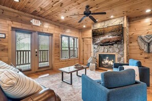 A log cabin interior with a fireplace, seating area, and an exit sign. - Gatlinburg 7BR | Theater + 2 Game Rooms (Gatlinburg)
