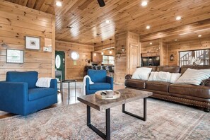 A cozy interior with wooden walls, a blue sofa, a brown leather couch, and a coffee table. - Gatlinburg 7BR | Theater + 2 Game Rooms (Gatlinburg)