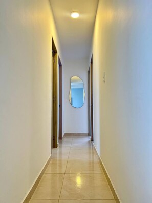 A corridor with a round mirror on the wall, a light fixture on the ceiling, and a door on the left. - Casa Arena Confort Torices (Cartagena)