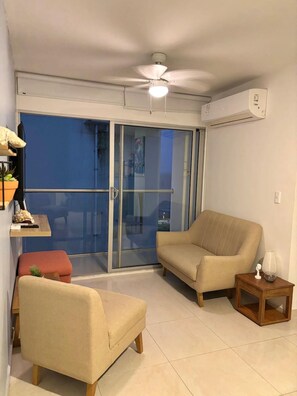 A living room with a sofa, armchair, and a small table with a lamp. - Casa Arena Confort Torices (Cartagena)