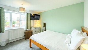 A bedroom with a bed, a TV, a dresser, a lamp, and a window with curtains. - 2 Bed home, close to the hospital and town centre - Pass the Keys (Shrewsbury)
