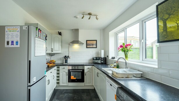A modern kitchen with white cabinets, a built-in oven, a dishwasher, and a window with a view of the outdoors. - 2 Bed home, close to the hospital and town centre - Pass the Keys (Shrewsbury)